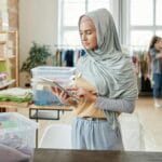 Wspierasz lokalnie? Jak pomagać w Tarnobrzegu, gdy nie możesz być na Finale Wolontariuszka w hidżabie sortuje ubrania w lokalnym punkcie darów