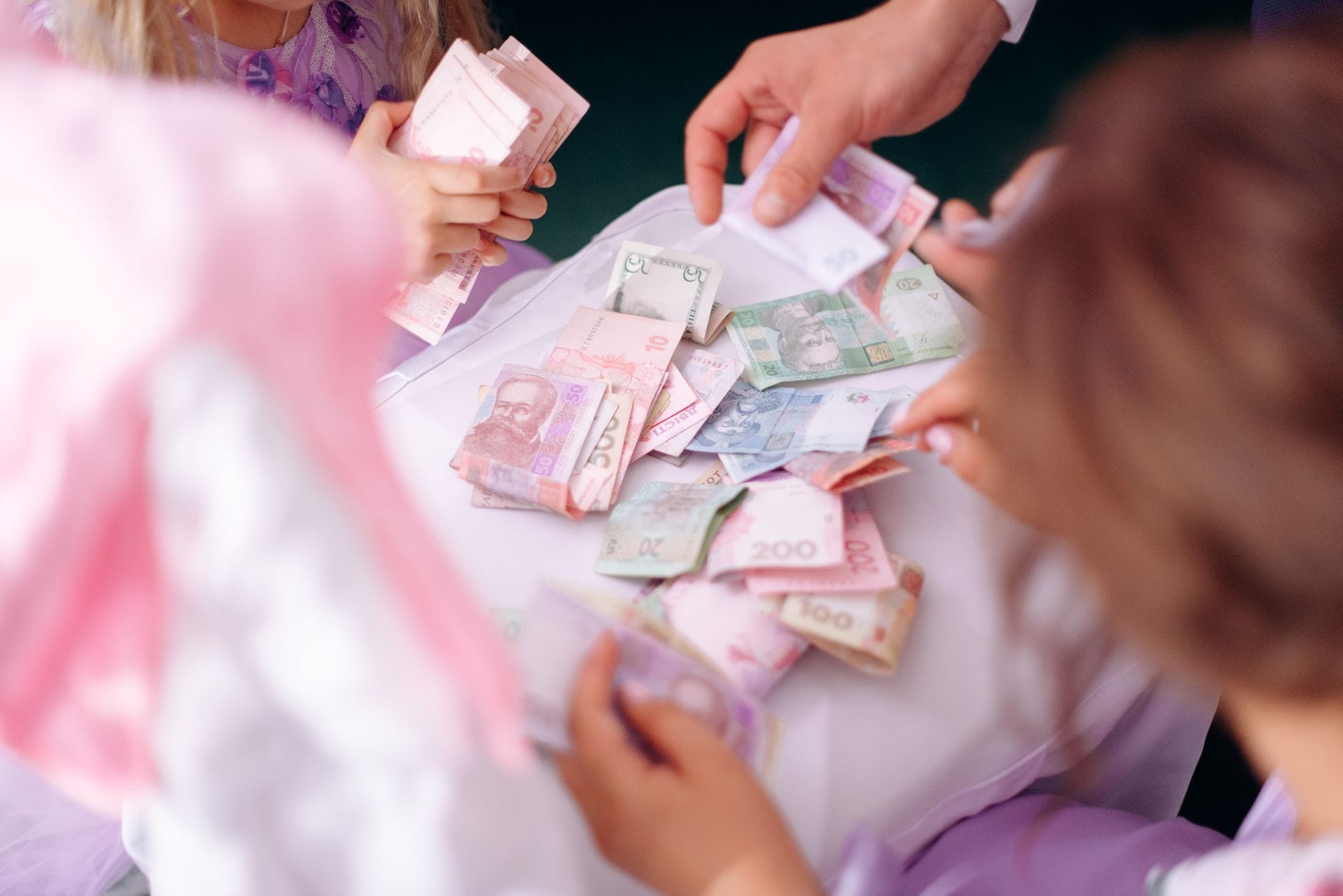 Aukcje WOŚP jako lekcja finansów dla młodych Dziecko i dorosły liczą kolorowe banknoty na stole podczas nauki finansów